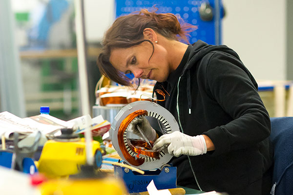 Woman winding an electric motor by hand in a workshop.