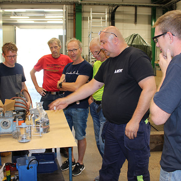 En gruppe menn som får trening på transformatorer i et verksted.